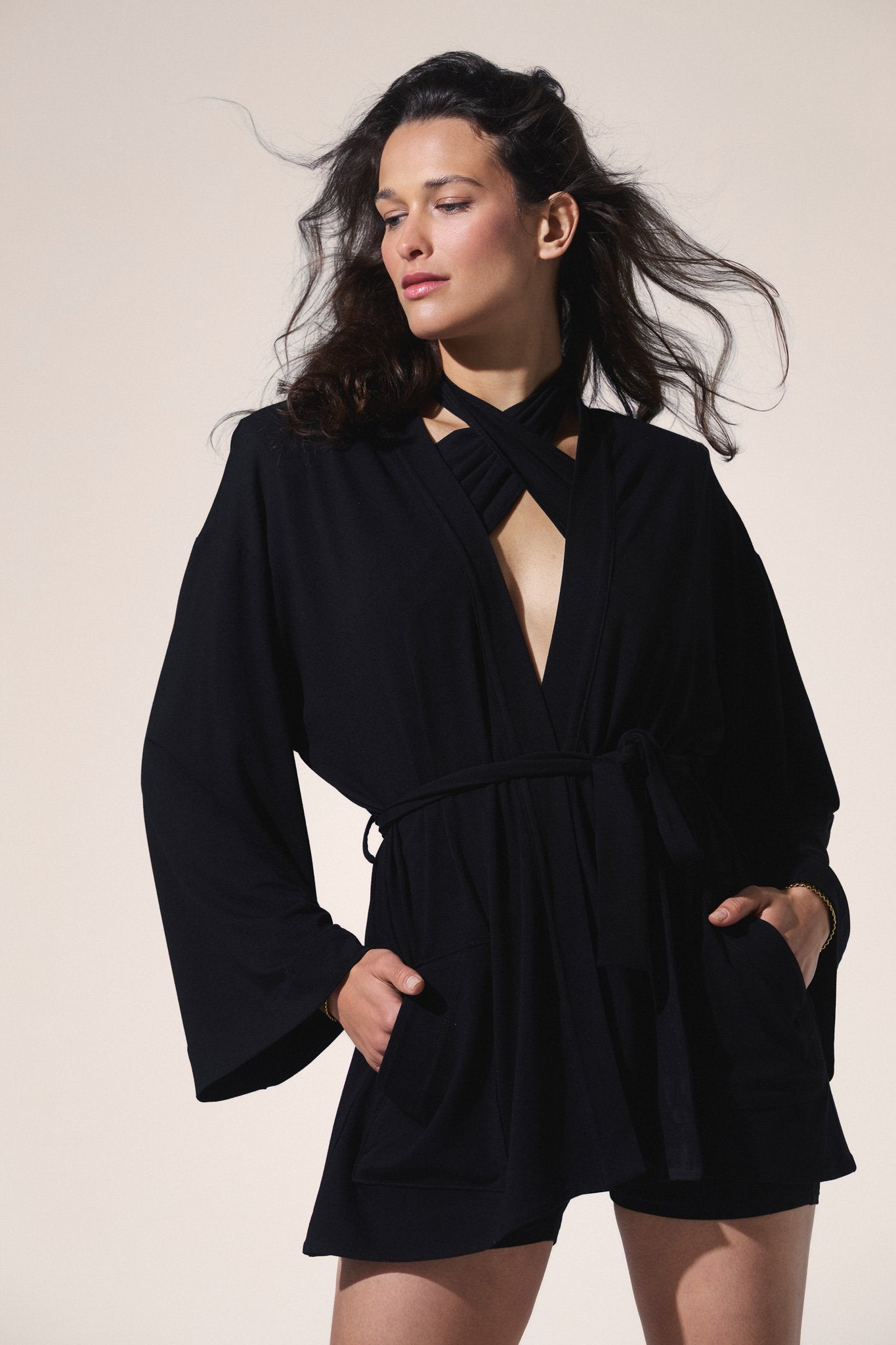 Woman wearing a black set with top and long sleeves kimono against a beige background