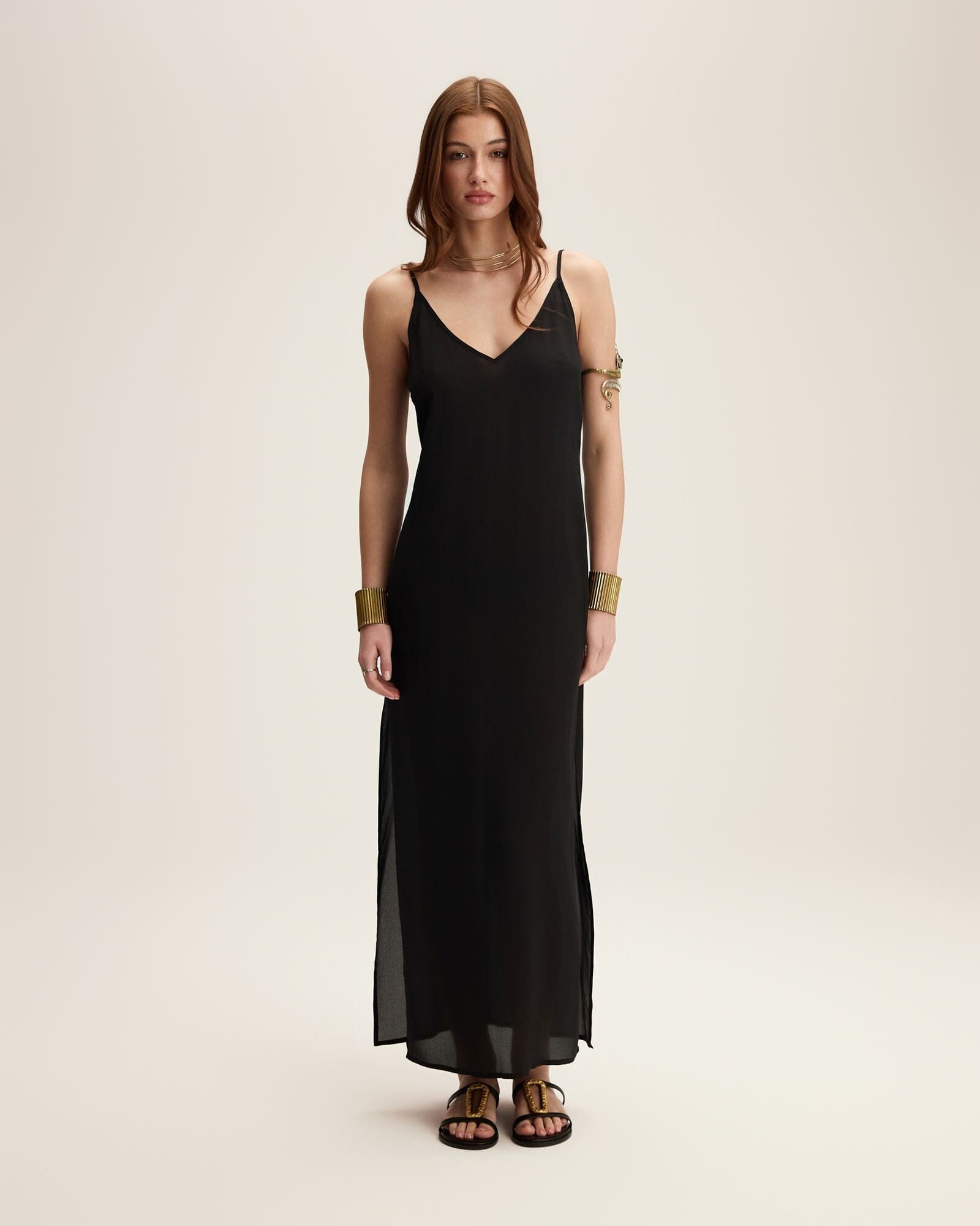 Woman wearing a black slip dress on a beige background