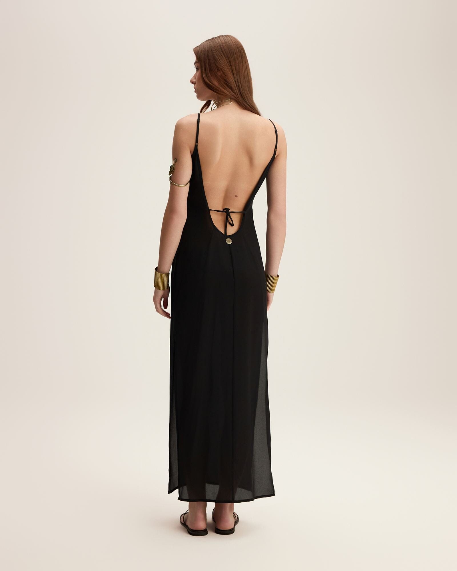 Woman wearing a black dress with a backless design on a beige background