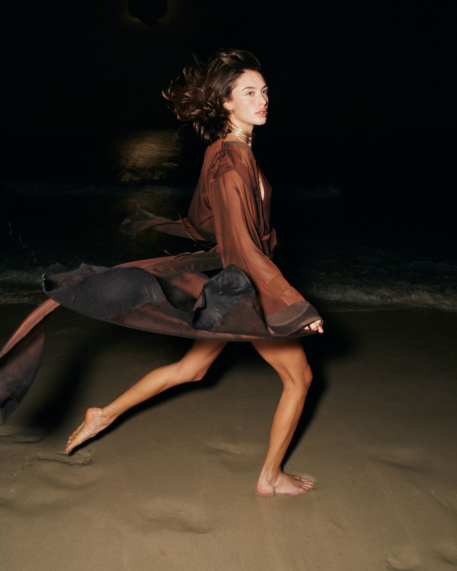 Woman in a flowing dress on a dark beach