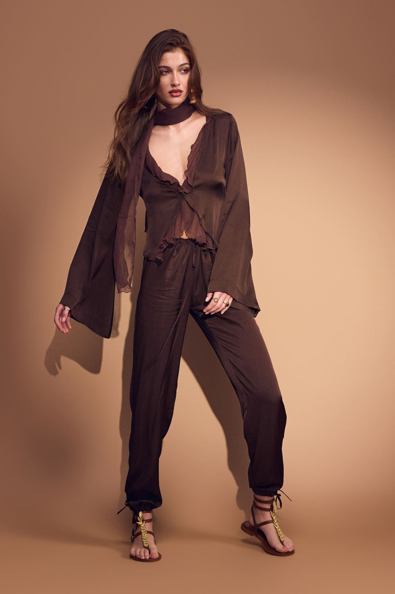 Woman wearing a brown outfit against a beige background