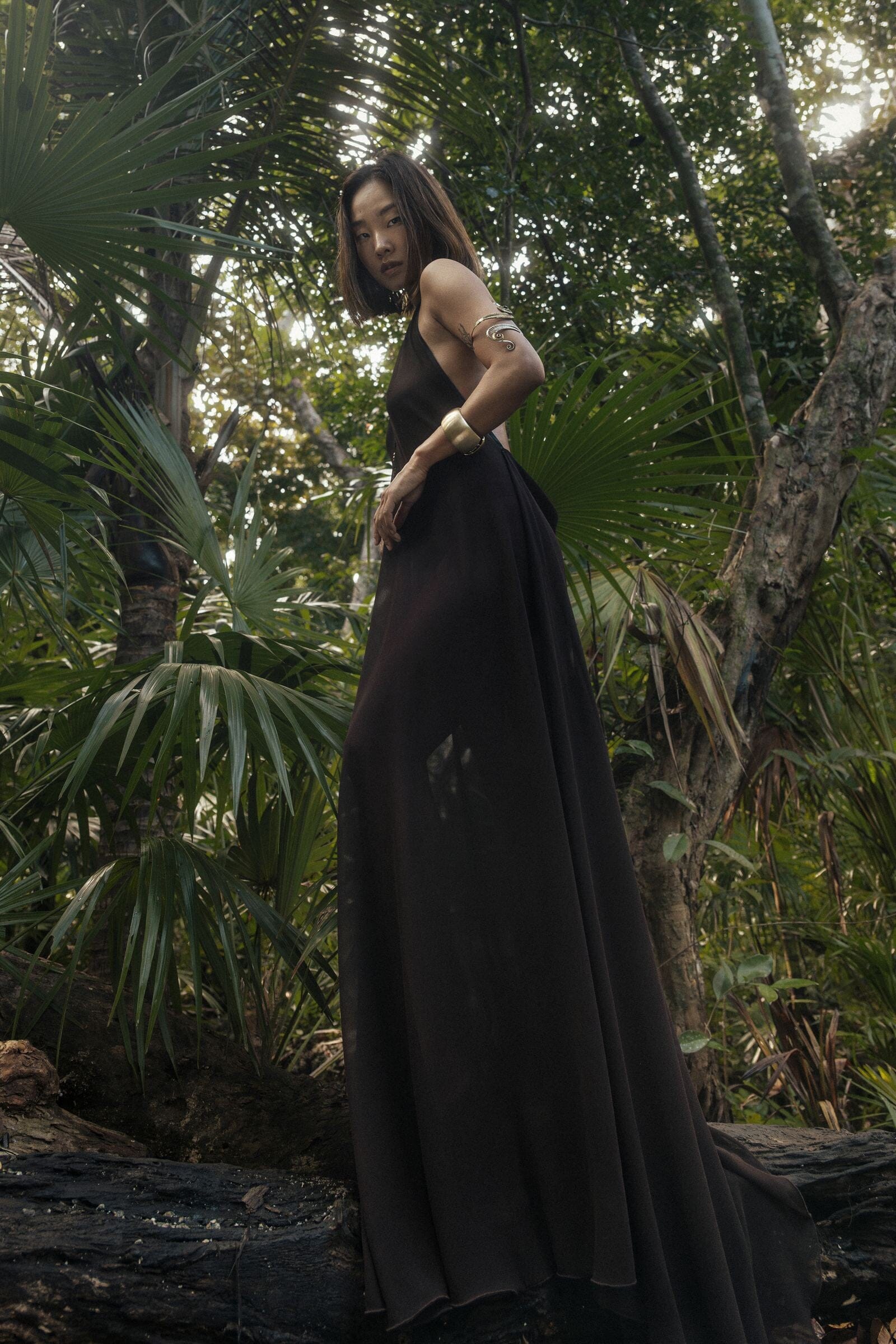 Woman in a brown dress standing in a tropical forest