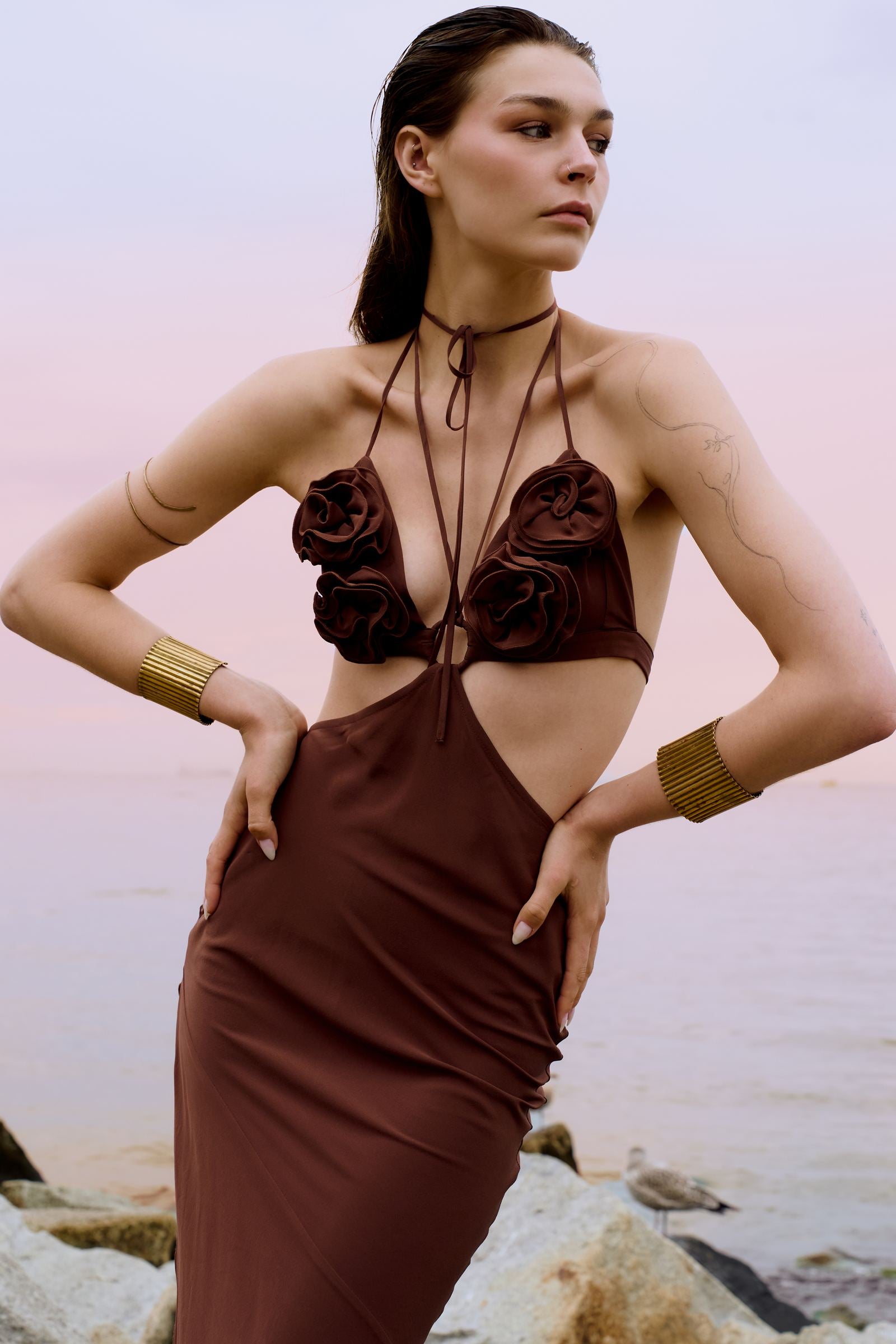 Woman wearing a brown dress with floral details by the beach