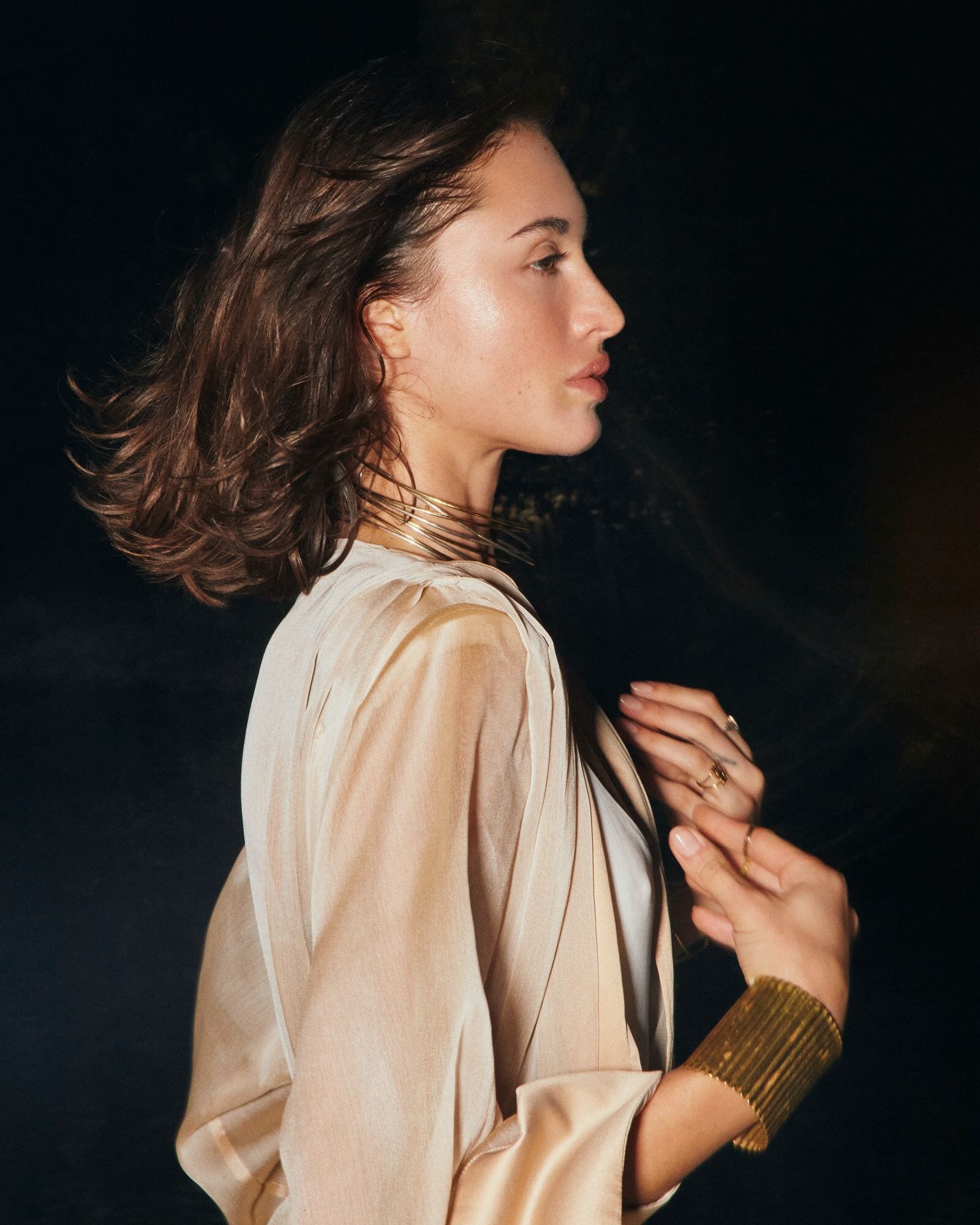 Woman wearing a beige satin robe against a dark background