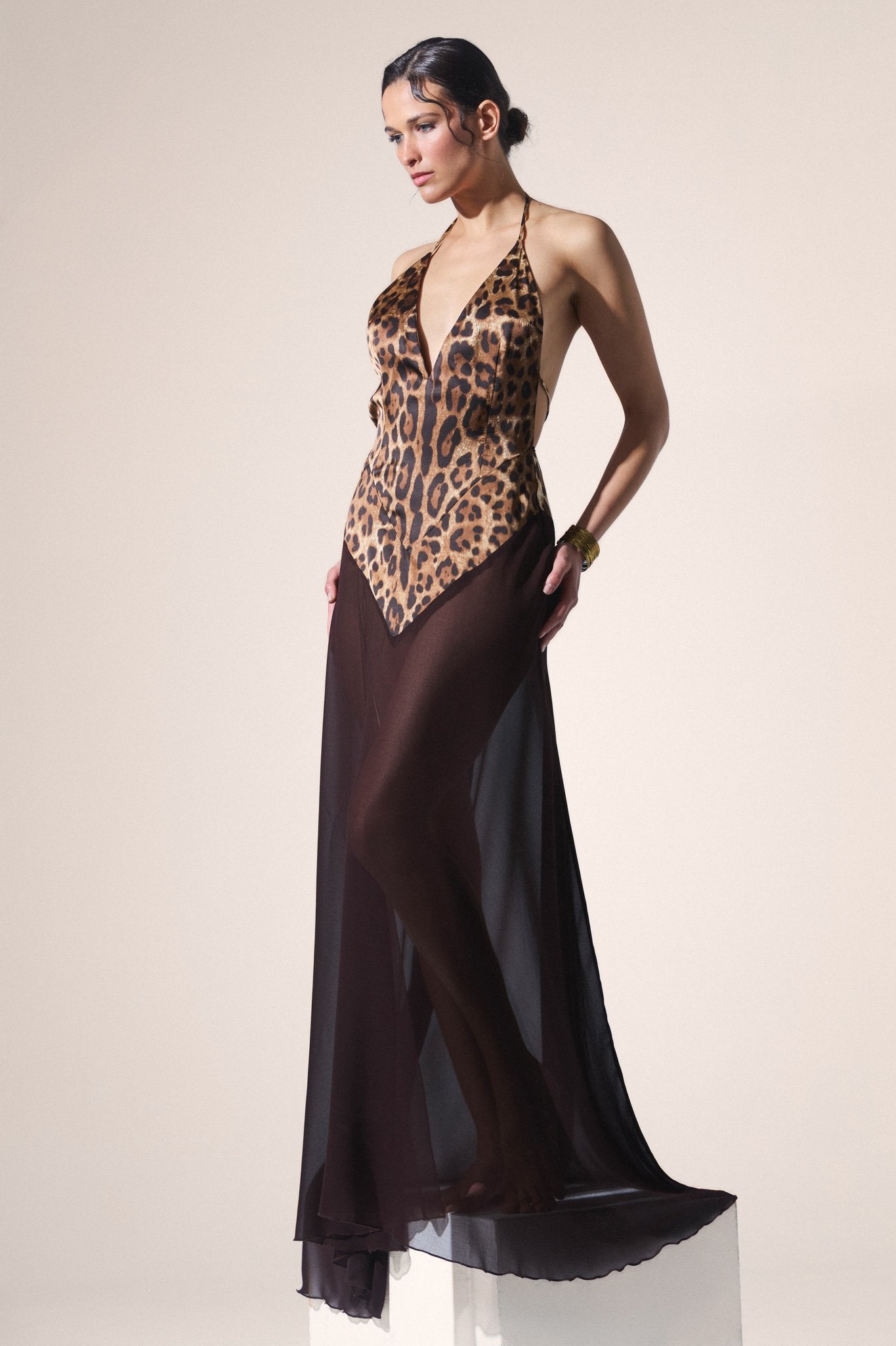 Woman wearing a leopard print dress with a long brown sheer skirt on a plain background