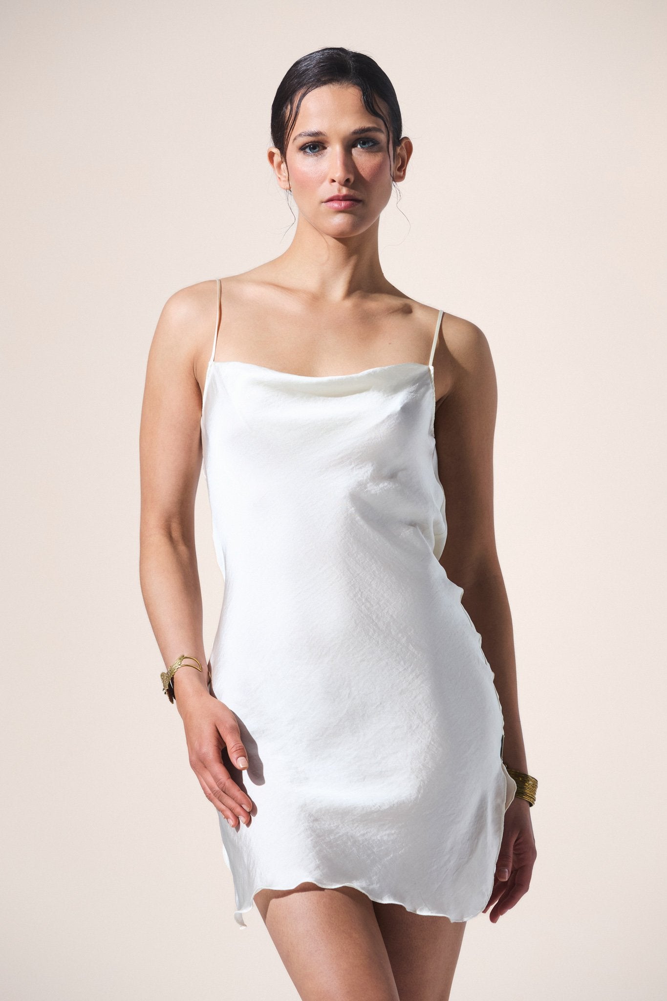 Woman wearing a white slip dress against a plain background