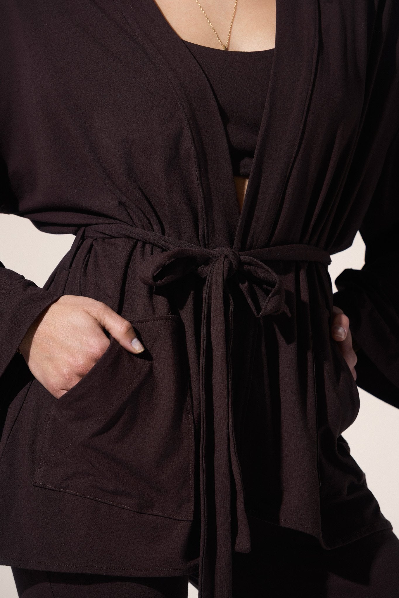 Close-up of a person wearing a dark brown robe with a belt.