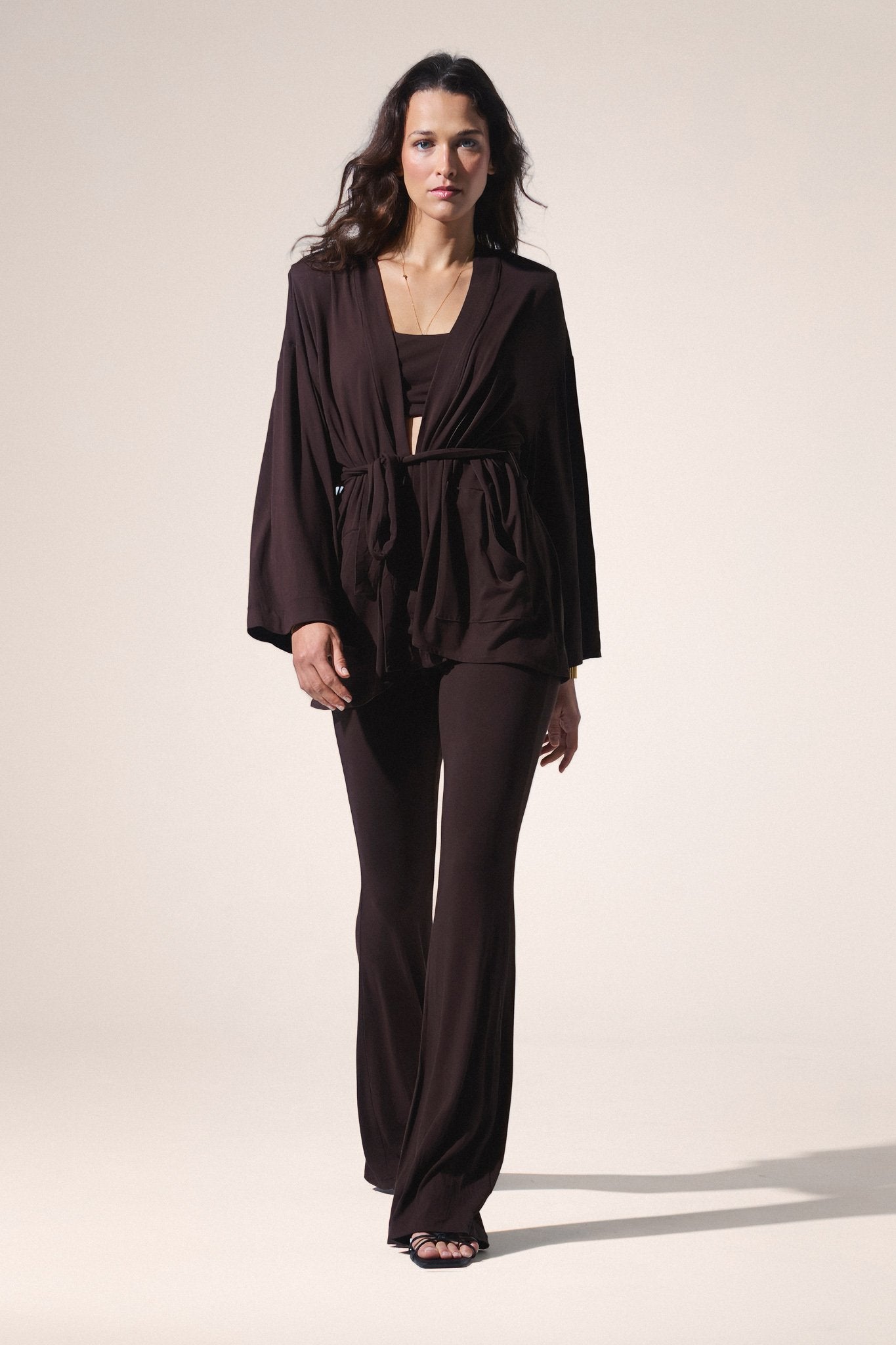 Woman wearing a brown outfit on a plain background