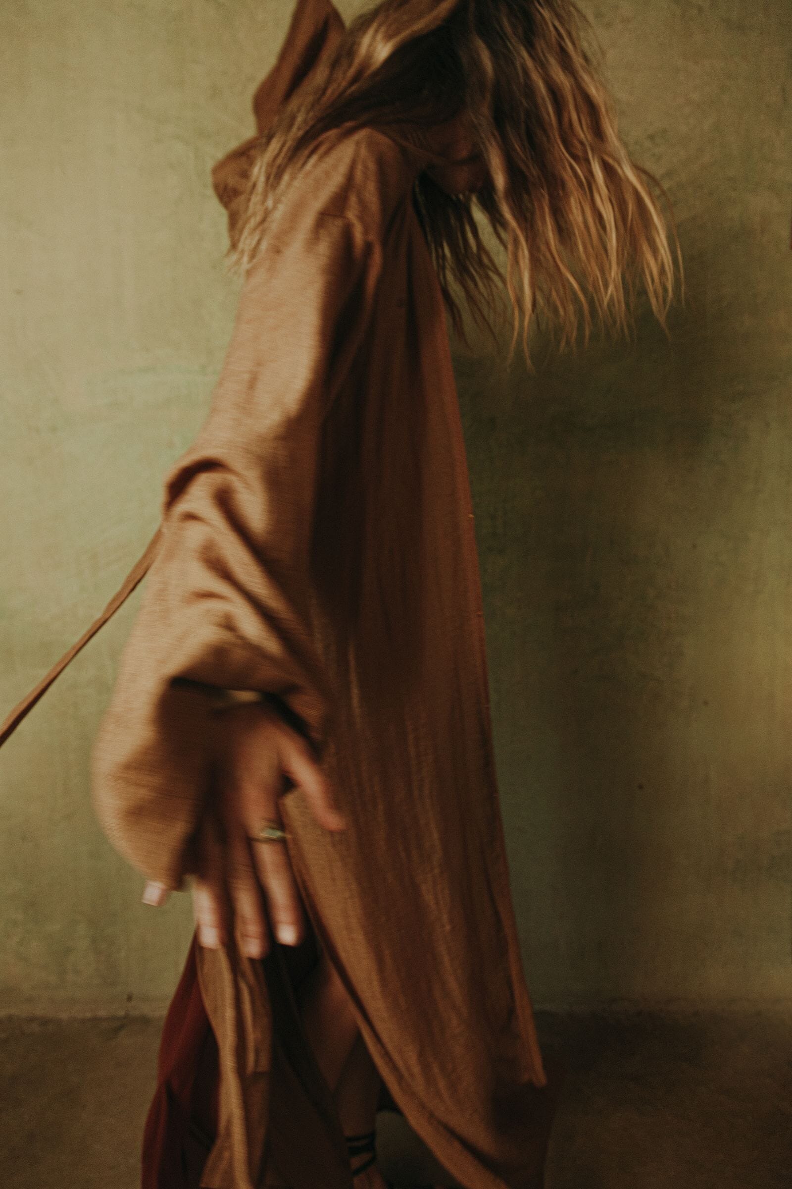 Person wearing a gold coat with a hood against a plain background