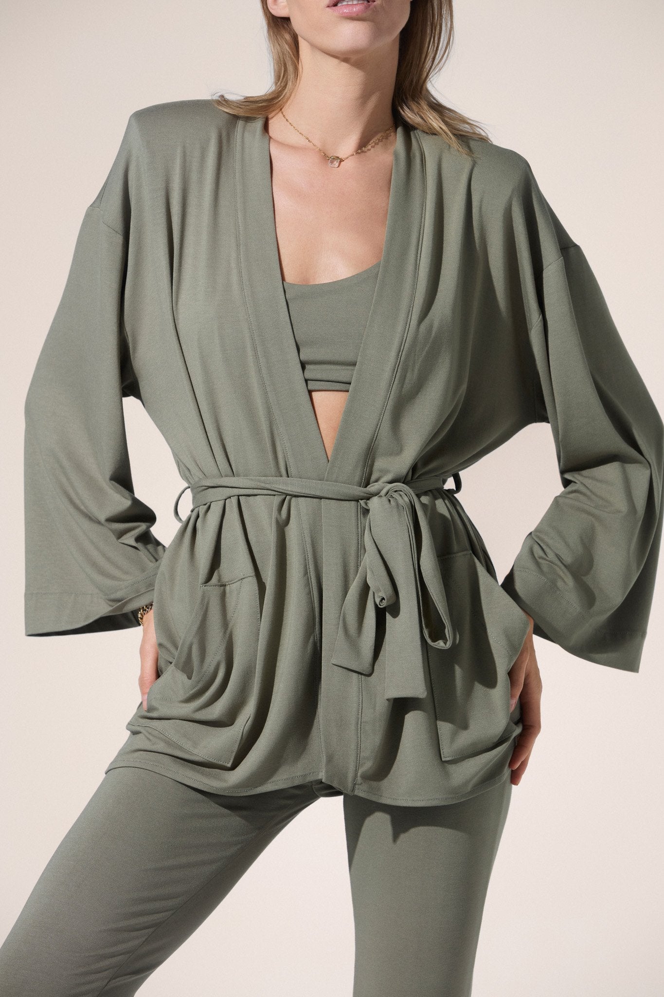 Woman wearing a green set with a matching cardigan on a beige background